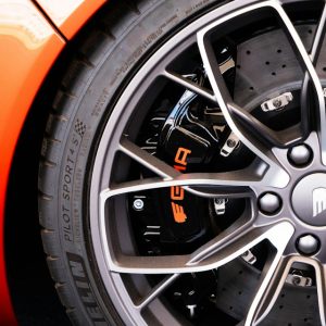 Close-up of a performance car wheel, brake caliper and titanium lug bolts